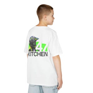 May include: White t-shirt with a graphic on the back featuring a motocross helmet design, the number 47, and the word "KITCHEN" in black. The design includes green and black accents.