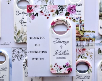 May include: Set of white ceramic bottle openers with floral designs and the names of couples and their wedding dates. The text "Thank you for celebrating with us!" is printed on one of the bottle openers.