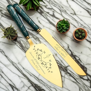 May include: Gold cake server and knife set with green marble handles. The server is engraved with the text "Serve the LORD with gladness, Psalm 100:2" and the initials "A J". The knife is engraved with the text "December 2024, Sakshi & Arjun".