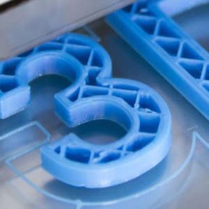 Peut inclure: Une imprimante 3D créant un modèle en plastique bleu des lettres "3D".