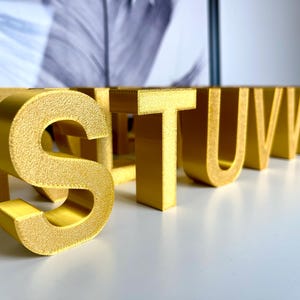 Op de afbeelding: Gouden letters van het alfabet, beginnend met de letter "S" en eindigend met de letter "X".