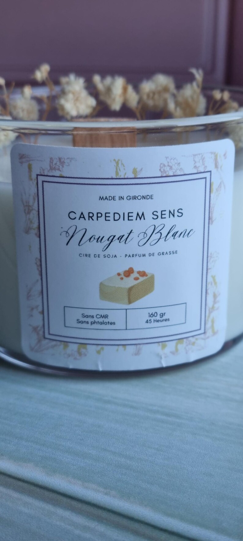 Pu&ograve; includere: Un barattolo di candela bianco con un'etichetta bianca che dice "CARPEDIEM SENS Nougat Blanc" in testo nero. L'etichetta dice anche "CIRE DE SOJA - PARFUM DE GRASSE" in testo nero pi&ugrave; piccolo. L'etichetta ha una piccola illustrazione di una barretta di torrone. L'etichetta dice anche "Sans CMR" e "Sans phtalates" in testo nero. L'etichetta dice anche "160 gr" e "45 Ore" in testo nero.