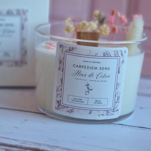 Pu&ograve; includere: Una candela bianca di cera di soia in un barattolo di vetro trasparente con uno stoppino di legno. La candela &egrave; decorata con fiori secchi e ha un'etichetta che recita "Carpediem Sens Fleur de Coton, Cire de Soja, Parfum de Grasse, Sans CMR, Sans Phthalates, 160 gr, 45 Heures".