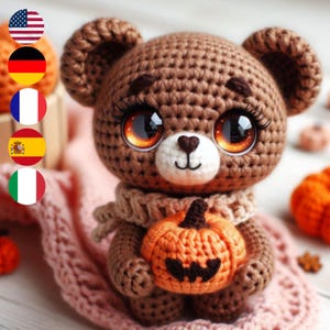 May include: A brown crocheted teddy bear with large, sparkly eyes holds a crocheted orange pumpkin with a jack-o'-lantern face. The bear is wearing a brown and white scarf.