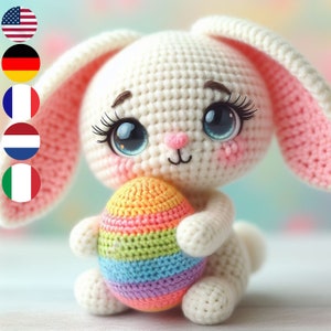 May include: A white crocheted bunny holding a colorful crocheted Easter egg. The bunny has large blue eyes with eyelashes and a pink nose.