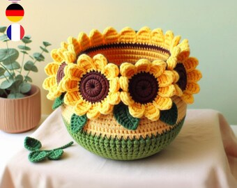 May include: A crocheted sunflower basket with green leaves. The basket is made of yellow and green yarn and features three large sunflowers.