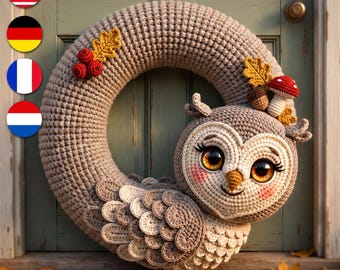 May include: A circular crochet wreath in light brown yarn featuring a large owl figure with oversized amber eyes, long eyelashes, and pink cheeks. The wreath is decorated with small red berries, a brown acorn, and a red and white spotted mushroom.