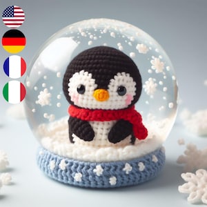 Puede incluir: Una figurita de pingüino de crochet dentro de una bola de nieve de vidrio con una base de crochet azul. El pingüino lleva una bufanda roja y tiene ojos negros y un pico amarillo.