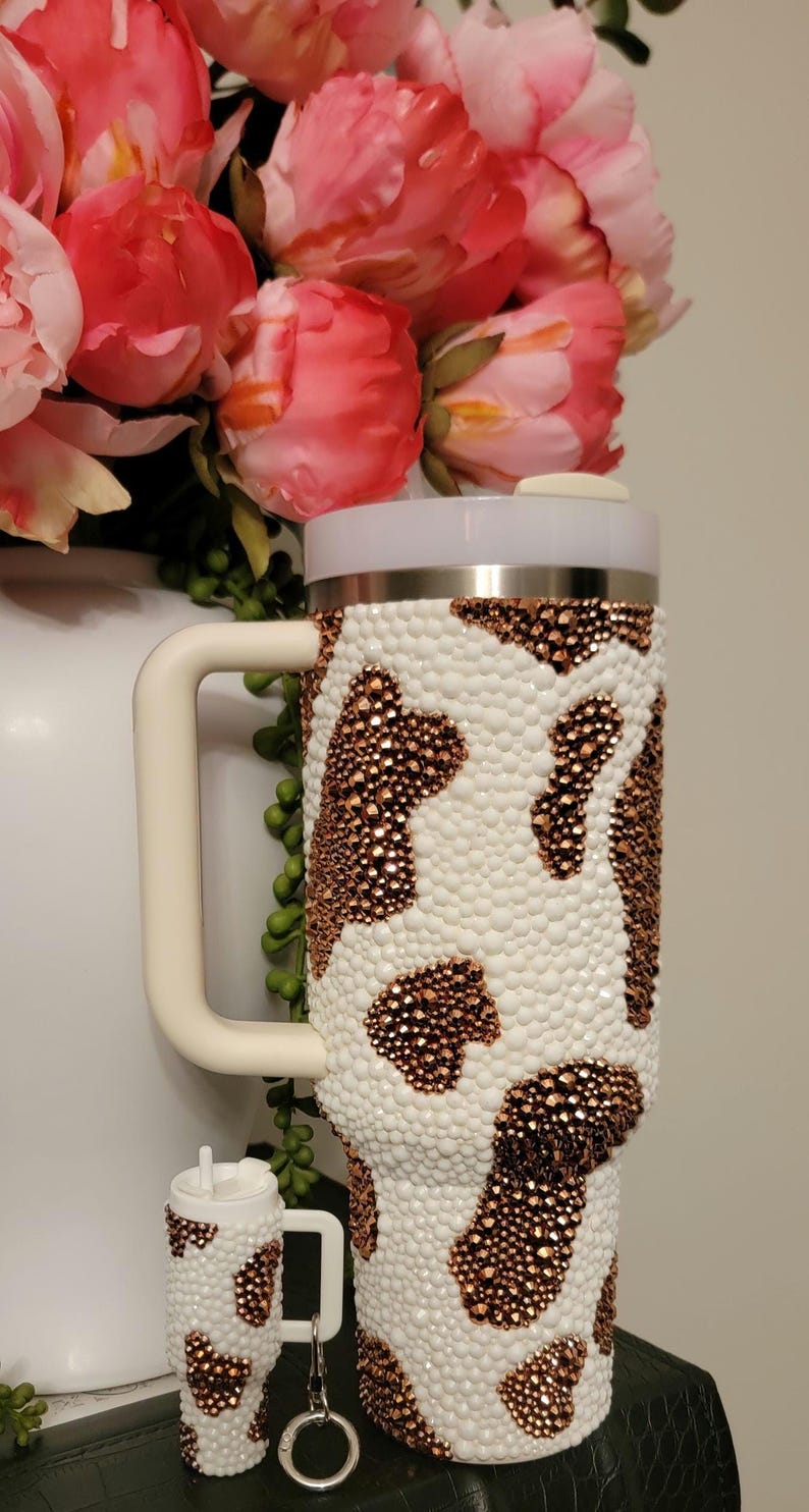 May include: A white ceramic mug with a black handle and the text "But first, coffee" in a handwritten style. The mug is on a white surface. The mug is approximately 4 inches tall.