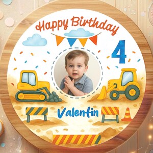 Op de afbeelding: Een ronde verjaardagstaart met een houten frame, versierd met een foto van een kind en illustraties met een bouwthema. De taart toont de tekst "Happy Birthday", het cijfer "4" en de naam "Valentin".