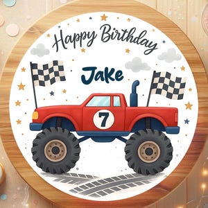 May include: A round cake featuring a red monster truck design, the number 7, and the name "Jake". The cake is decorated with checkered flags, stars, and the words "Happy Birthday".