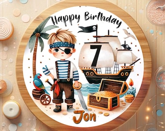 May include: A round cake with a pirate theme. The cake features a cartoon pirate with an eye patch, a pirate ship, a treasure chest, and the words "Happy Birthday" and "Jon". The number "7" is also displayed.
