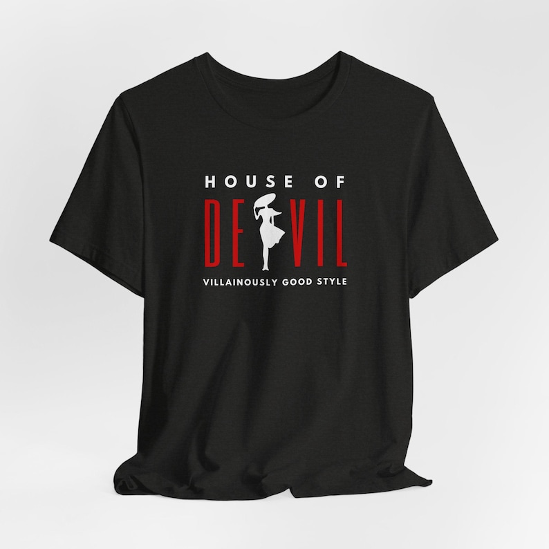 Top line of shirt reads HOUSE OF, followed by the word DE VIL, with the silhouette of a woman in between the E and the V. Below are the words Villainously Good Style. Shown is the Black Heather shirt color option.