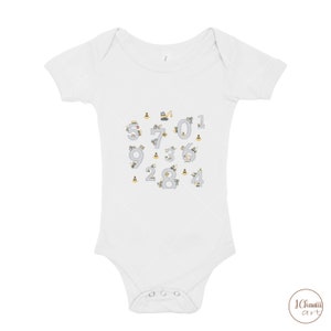 K&ouml;nnte beinhalten: Wei&szlig;er Baby-Strampler mit kurzen &Auml;rmeln und einem Design aus den Zahlen 0-9, die aus Baufahrzeugen und Verkehrskegeln bestehen.