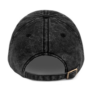 May include: Black denim baseball cap with a classic design. The cap has a structured crown and a curved brim. The back of the cap features a metal buckle closure.