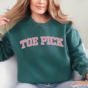 May include: A teal green sweatshirt with the words "TOE PICK" in pink letters.