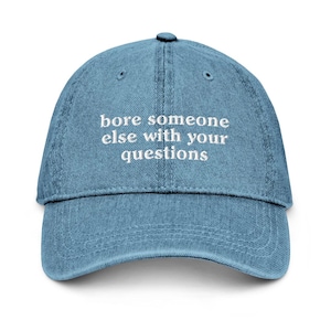 May include: A blue denim baseball cap with white embroidered text that reads "bore someone else with your questions".