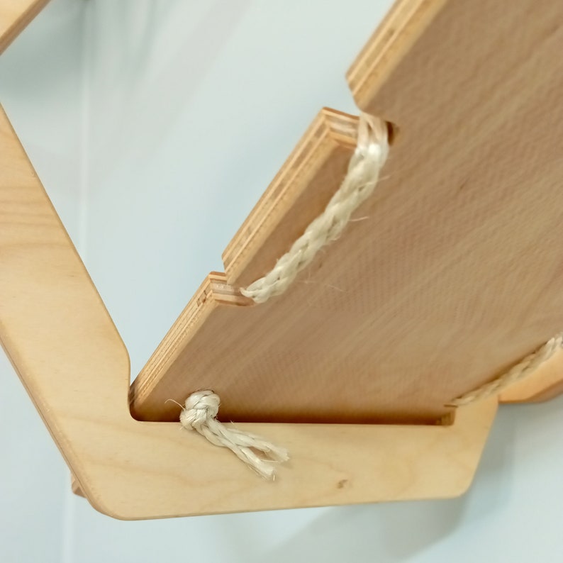 May include: A wooden shelf with a natural finish and rope accents. The shelf is attached to the wall with a bracket.