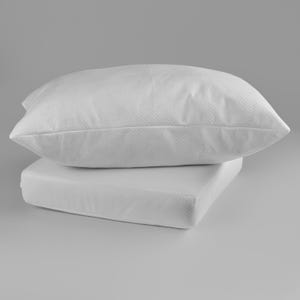 Puede incluir: Dos almohadas blancas, una rectangular y otra cuadrada, apiladas una encima de la otra. Ambas almohadas tienen una superficie texturizada. El fondo es gris claro liso.