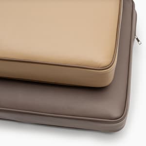May include: Two rectangular cushions with a smooth, textured surface. The top cushion is light beige, and the bottom cushion is dark brown. Both cushions feature piped edges and a visible metal zipper pull on the side of the dark brown cushion.