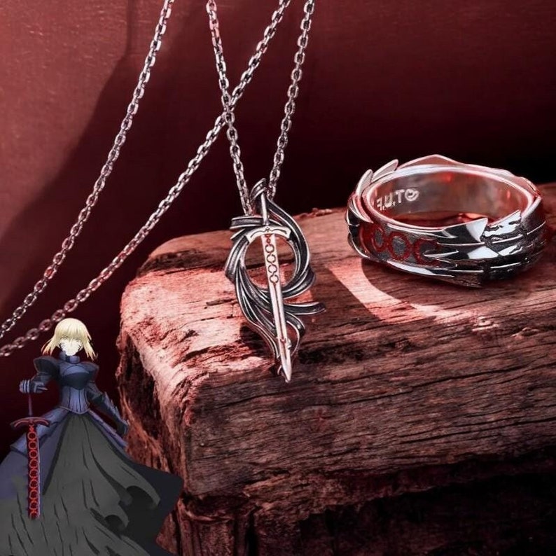 May include: A silver necklace with a sword pendant and a silver ring with a red and silver design. The ring has the text "F.U.T.O." engraved on it.