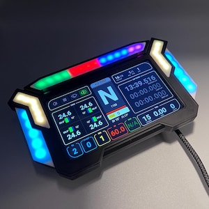 Può includere: Un display digitale nero con varie letture di dati, tra cui velocità e tempi sul giro. Il dispositivo ha uno schermo rettangolare con luci a LED colorate sulla parte superiore e sui lati. Un cavo si estende dalla parte inferiore.