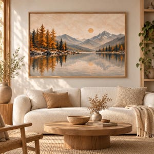 May include: A rectangular wall art print featuring a landscape painting of a calm lake reflecting a mountain range and a forest of orange and green trees under a pale sun. The artwork is displayed in a thin wooden frame on a neutral wall.