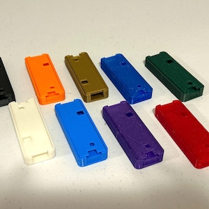 May include: Assortment of ten 3D printed cases in various colors, including black, orange, gold, blue, green, white, purple, and red. The cases are all the same size and shape, and they have a rectangular design.