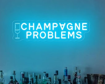 May include: A blue neon sign with the text "Champagne Problems" and a glass of champagne icon. The sign is hanging on a wall above a wooden cabinet with a collection of liquor bottles.