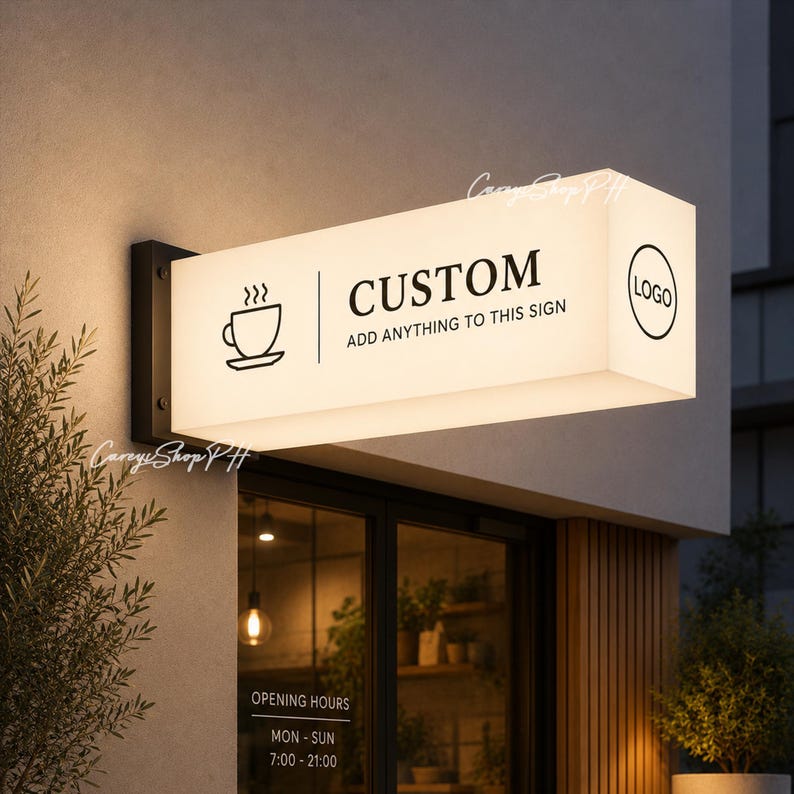 Pode incluir: Uma placa retangular iluminada com a palavra "CUSTOM" e um &iacute;cone de x&iacute;cara de caf&eacute;. A placa tamb&eacute;m inclui o texto "ADD ANYTHING TO THIS SIGN" e um espa&ccedil;o para um logotipo. A placa est&aacute; montada em uma parede acima de uma vitrine.