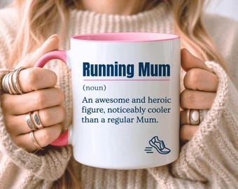 May include: A white ceramic mug with a pink interior and handle. The front features dark blue text that reads Running Mum (noun) An awesome and heroic figure, noticeably cooler than a regular Mum. A small dark blue graphic of a running shoe is below.