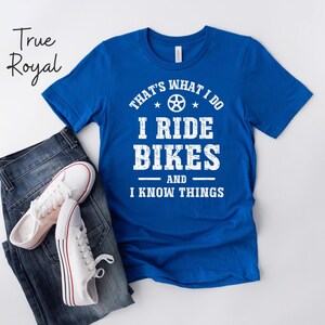 May include: A royal blue t-shirt with white text that reads "That's what I do I ride bikes and I know things". The text is in a distressed font and includes a small bicycle gear graphic.