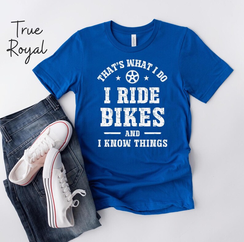 May include: A royal blue t-shirt with white text that reads "That's what I do I ride bikes and I know things". The text is in a distressed font and includes a small bicycle gear graphic.