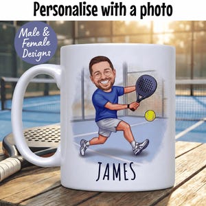 Puede incluir: Taza de cer&aacute;mica blanca con una ilustraci&oacute;n de dibujos animados de una persona jugando al p&aacute;del. La persona lleva una camisa azul y pantalones cortos blancos, sosteniendo una raqueta y una pelota amarilla. El nombre "JAMES" est&aacute; impreso en la parte inferior. El texto en la parte superior dice "Personaliza con una foto".