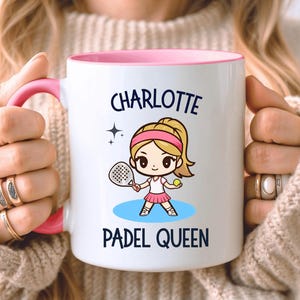 May include: White ceramic mug with a pink interior and handle, featuring the name "Charlotte" and a cartoon illustration of a girl playing padel. The text "Padel Queen" is also printed on the mug.