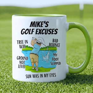 May include: White ceramic mug with a green handle and interior rim. The mug features the text "MIKE'S GOLF EXCUSES" and a cartoon illustration of a golfer. Additional text includes "TREE IN WAY", "GROUND NOT LEVEL", "BAD BOUNCE", "MY FOOT SLIPPED", and "SUN WAS IN MY EYES".