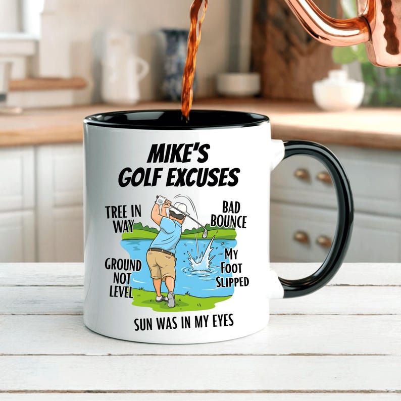 May include: A white ceramic mug with a black interior and handle. The mug features the text "Mike's Golf Excuses" and a cartoon illustration of a golfer. Excuses listed include "Tree in Way" and "Sun Was in My Eyes".