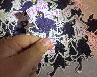 Könnte beinhalten: Ein Aufkleber mit einem Cartoon-Vogel mit lila Federn, der eine Pistole hält. Der Aufkleber trägt den Text "Flock or Glock" in Rosa und Weiß. Weitere Aufkleber mit dem gleichen Design sind im Hintergrund zu sehen.