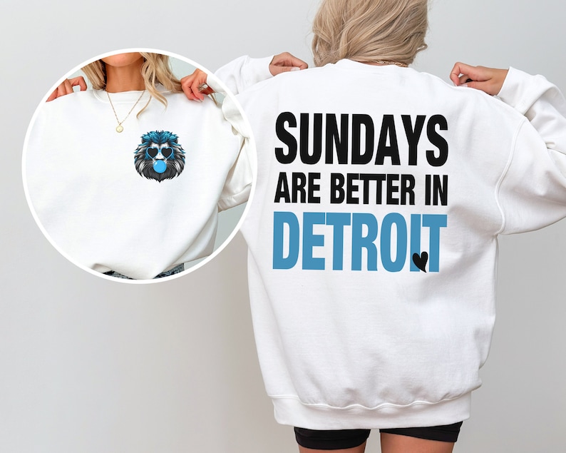 Puede incluir: Sudadera blanca con un gr&aacute;fico de le&oacute;n con gafas de sol azules y una burbuja de chicle en la parte delantera. La parte trasera de la sudadera tiene el texto "SUNDAYS ARE BETTER IN DETROIT" en negro y azul.