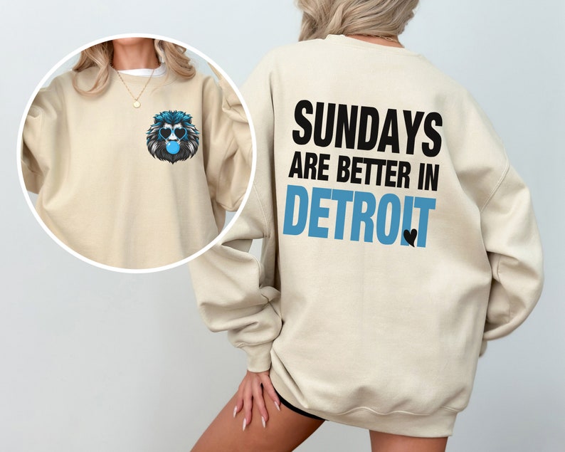 Puede incluir: Sudadera beige con un gr&aacute;fico de le&oacute;n con gafas de sol y soplando una burbuja en la parte delantera. La parte trasera de la sudadera tiene el texto "SUNDAYS ARE BETTER IN DETROIT" en negro y azul, con un peque&ntilde;o coraz&oacute;n negro.