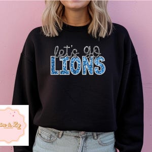May include: Black sweatshirt with the text "Let's go Lions" in blue glitter lettering.