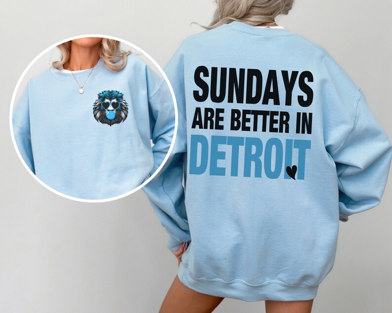 Puede incluir: Sudadera azul claro con el texto "SUNDAYS ARE BETTER IN DETROIT" en la espalda. Un gr&aacute;fico de le&oacute;n con gafas de sol y una burbuja de chicle est&aacute; en la parte delantera. Estilo casual.