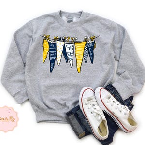 May include: Gray sweatshirt with a graphic of pennants that say "Go Blue", "Fight Win", "Moving On", and "Game Day".
