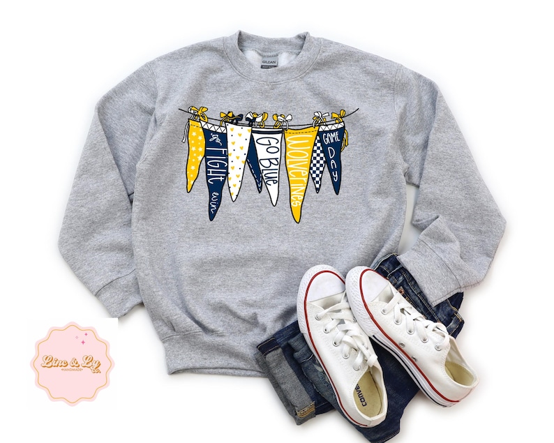 May include: Gray sweatshirt with a graphic of pennants that say "Go Blue", "Fight Win", "Moving On", and "Game Day".