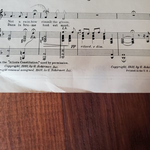 May include: A sheet of music with the title "Not a rain-bow" and the text "Dans la bru-me tout est mort. LA." The music is written in a traditional style with notes and clefs. The text "Copyright, 1910, by G. Schirmer, Inc." and "Copyright renewal assigned, 1938, to G. Schirmer, Inc." is printed at the bottom of the page.