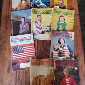 May include: A collection of vintage "The Workbasket" magazines featuring various knitting and crocheting patterns. The magazines are from the 1970s and feature colorful covers with images of women wearing knitted garments.