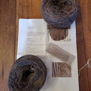 May include: Two skeins of yarn, one dark purple and green, the other a mix of brown, orange, and blue. The yarn is labeled "LINO 65% Silk, 35% Linen, 100m/100g, Hand dyed in Canada - One of a Kind".