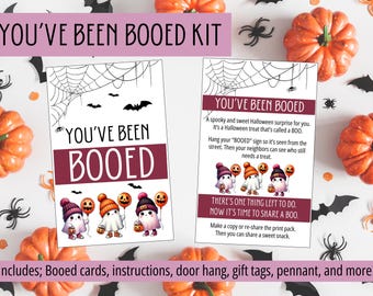 May include: Halloween-themed kit with cards that say "YOU'VE BEEN BOOED". The cards feature illustrations of ghosts holding balloons and pumpkins. The kit includes instructions, door hang, gift tags, and more. Pumpkins, spiders, and bats decorate the background.