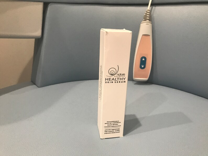May include: White box with a black and white logo of a snail with the text "nature cosmeceuticals" and "HEALTHY SKIN SERUM".
