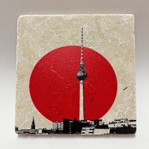 Könnte beinhalten: Eine Schwarzweißillustration des Berliner Fernsehturms mit einem roten Kreis dahinter. Der Turm befindet sich in der Mitte des Bildes und der Kreis dahinter. Der Turm ist ein hohes, schlankes Bauwerk mit einer Kugel auf der Spitze. Der Kreis ist eine einfache, durchgehende rote Form.
